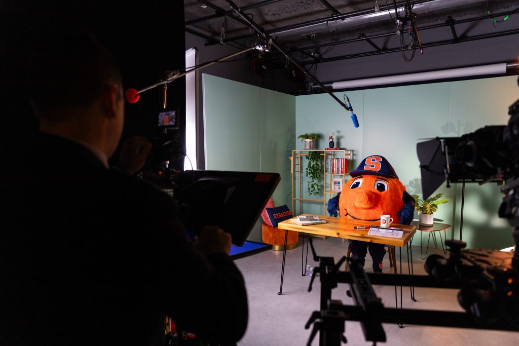 Otto the Orange sits at a desk in a virtual classroom.