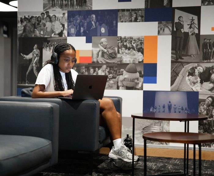 An image of a student sitting with her laptop with her headphones on. / Used for stackable learning blog post.