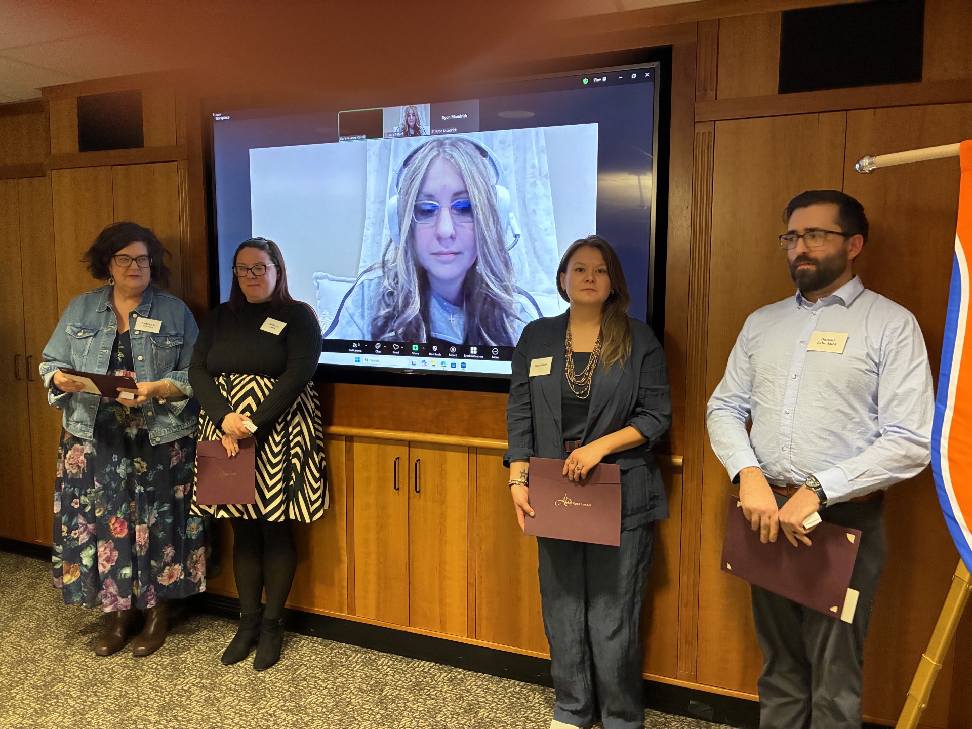 Five students take a group photo. Two students are on each side and one is in the middle on a Zoom video call. 