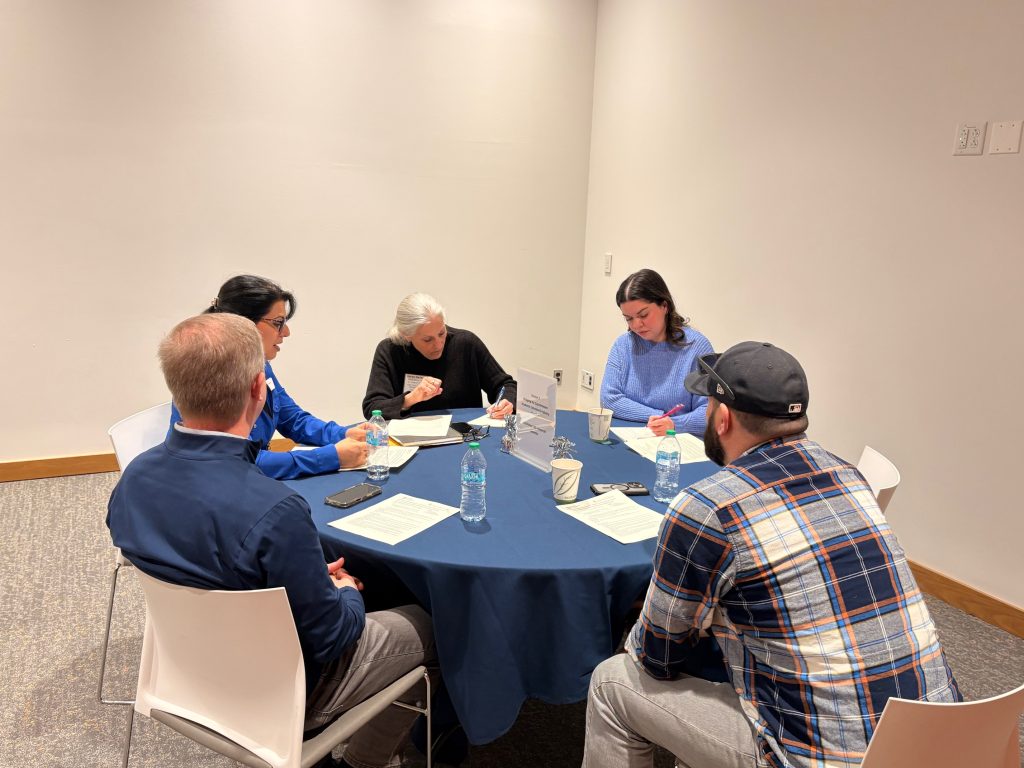 Five event attendees gather at a round table table.