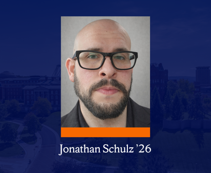 A headshot of a person with rectangle glasses and a beard. Below it is an aerial photo of campus buildings and trees with a dark blue overlay. Below the headshot is an orange rectangle and text that reads 