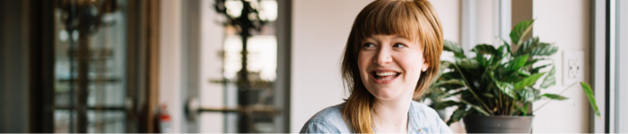 Woman smiling near plant at a coffee shop